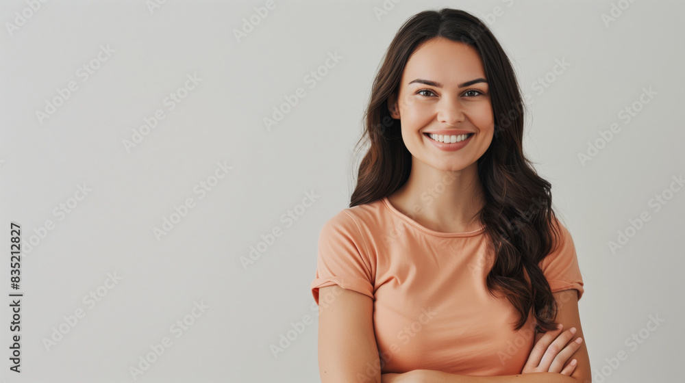Confident woman smiling in a peach shirt, arms crossed Confident woman smiling in a peach shirt, arms crossed
