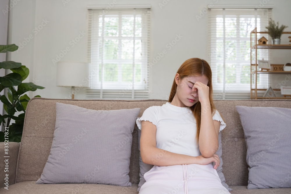 Asian woman feeling stressed and sitting on couch at home. Concept of mental health, stress, and anxiety Asian woman feeling stressed and sitting on couch at home. Concept of mental health, stress, and anxiety