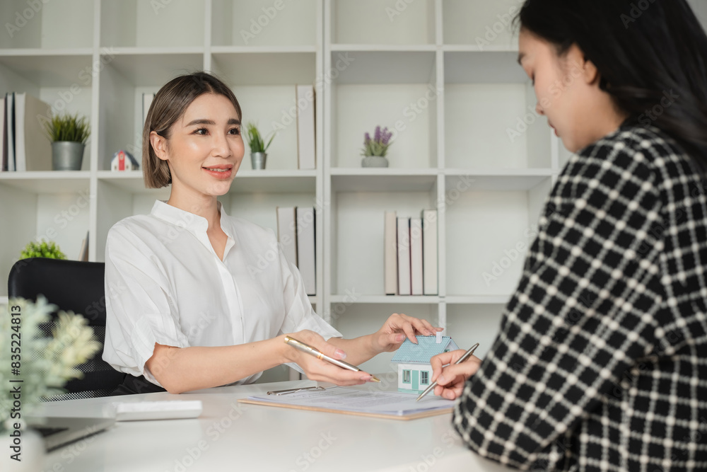 Two Asian businesswomen signing real estate documents at office desk. Concept of real estate agreement and professional consultation Two Asian businesswomen signing real estate documents at office desk. Concept of real estate agreement and professional consultation