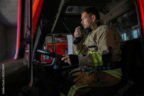 Photography Firefighter using portable radio set while driving fire truck