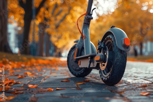 A scooter parked on a sidewalk in a park, perfect for a leisurely ride or a casual stroll photo