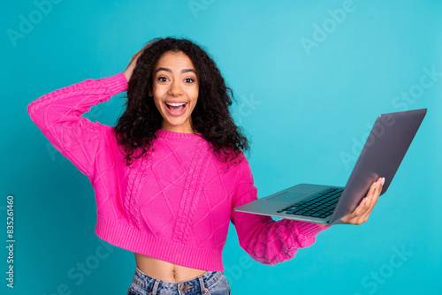 Photo portrait of lovely teen lady hold netbook excited dressed stylish pink garment isolated on cyan color background