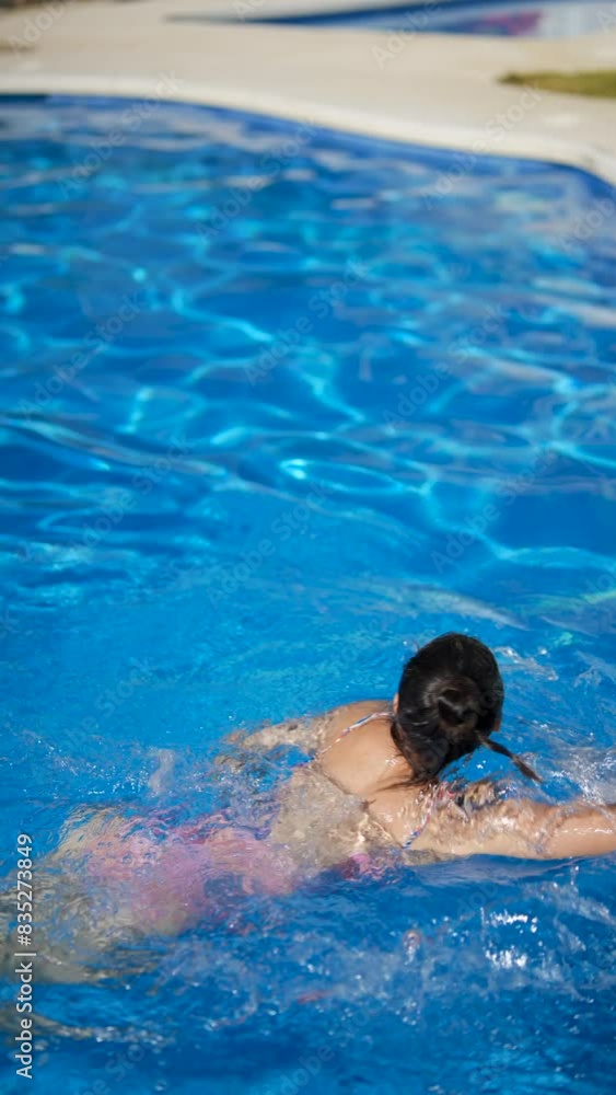A woman finding relaxation swimming in an outdoor pool under the sun on a sunny day A woman finding relaxation swimming in an outdoor pool under the sun on a sunny day