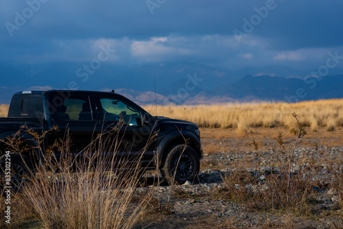 Safari, travel, extreme adventure or expedition in the desert. Desert with mountains on the horizon, dry grass and cracked earth. Off-road expedition. Mountains in the distance under storm sky.