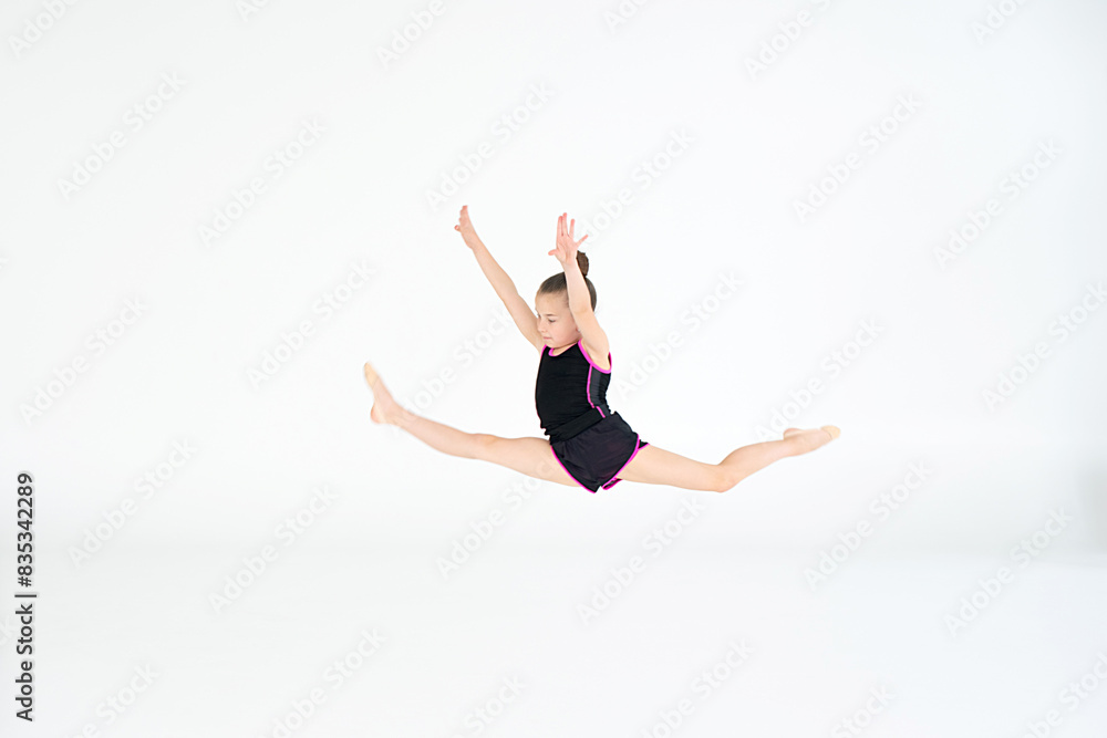 Beautiful gymnast athlete girl jumping in studio