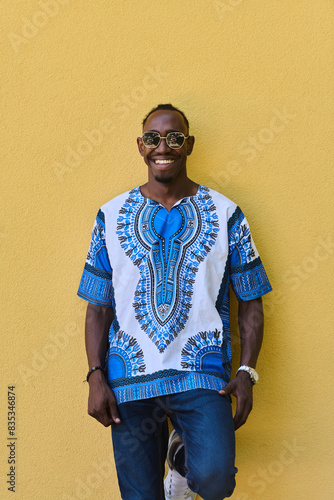 Sudanese Tradition Meets Modern Youth: African American Teen in Vibrant Traditional Attire Against a Yellow Backdrop