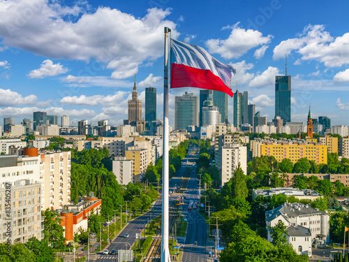 Polish national white and red flag against skyscrapers in Warsaw city center, aerial landscape under clear blue sky