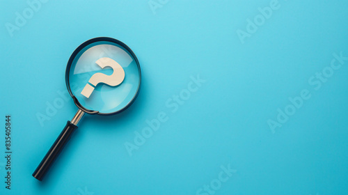 Magnifying glass searching for a question mark on a bright blue backdrop