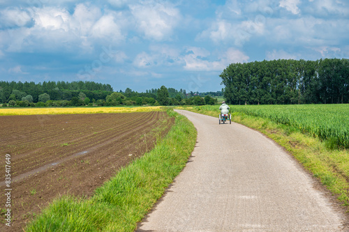 Woman with Down Syndrome on a tricycle through the agriculture field around Tienen, Belgium