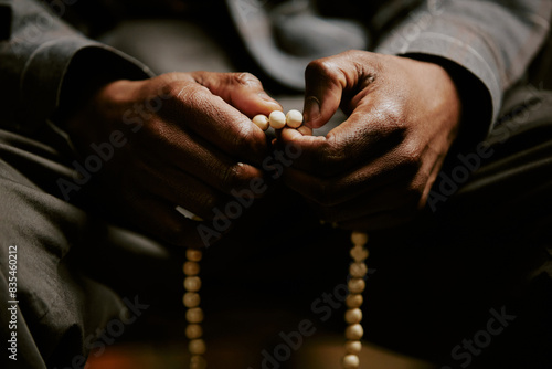 Closeup shot of unrecognizable African American male parishioner praying with rosary in hands photo