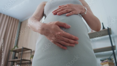 A close-up view a pregnant woman's hands stroking her belly, symbolizing love and anticipation for the life growing inside.