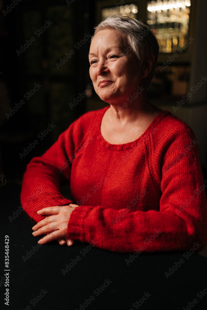 Vertical portrait of cheerful mature adult woman receiving good forecasting future during divination session sitting at table in dark room, by light of burning candle. Concept of prophecy, prediction. Vertical portrait of cheerful mature adult woman receiving good forecasting future during divination session sitting at table in dark room, by light of burning candle. Concept of prophecy, prediction.