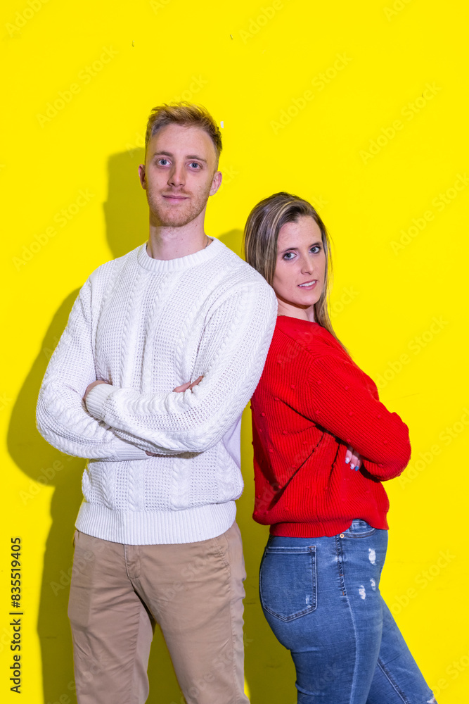 A man and a woman are standing next to each other on a yellow background A man and a woman are standing next to each other on a yellow background