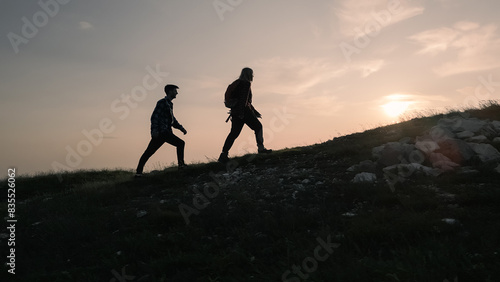 Wallpaper Mural Two silhouettes, male and female, conquering a mountain peak, giving high fives and enjoying the landscape during a romantic sunset, aerial shot. Torontodigital.ca