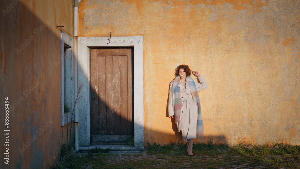 Relaxed woman leaning rustic building with textured doorway at sunset sunlight. Relaxed woman leaning rustic building with textured doorway at sunset sunlight.