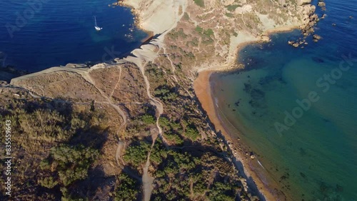 Qarraba Bay flat rock cape Malta, Aeriale stablishing shot in the morning sunlight showing hiking trekking path and two beaches on both side. High quality 4k footage photo