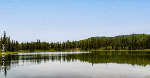 Reflections on lake that is surrounded by mountains and spruce trees.