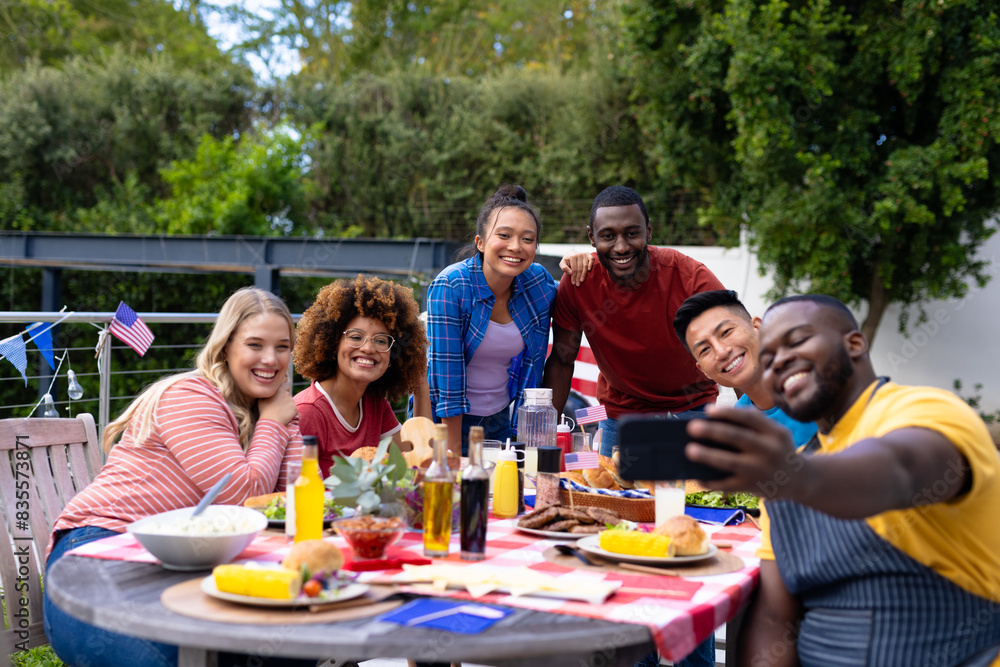 Happy diverse group of friends taking selfie and having dinner at balcony with flags of usa Happy diverse group of friends taking selfie and having dinner at balcony with flags of usa