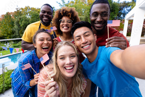Portrait of happy diverse group of friends taking selfie and holding flags of usa