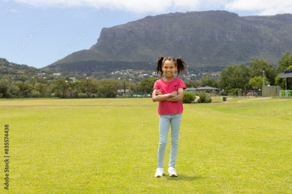 Biracial girl stands confidently in a park with mountains in the background, with copy space Biracial girl stands confidently in a park with mountains in the background, with copy space