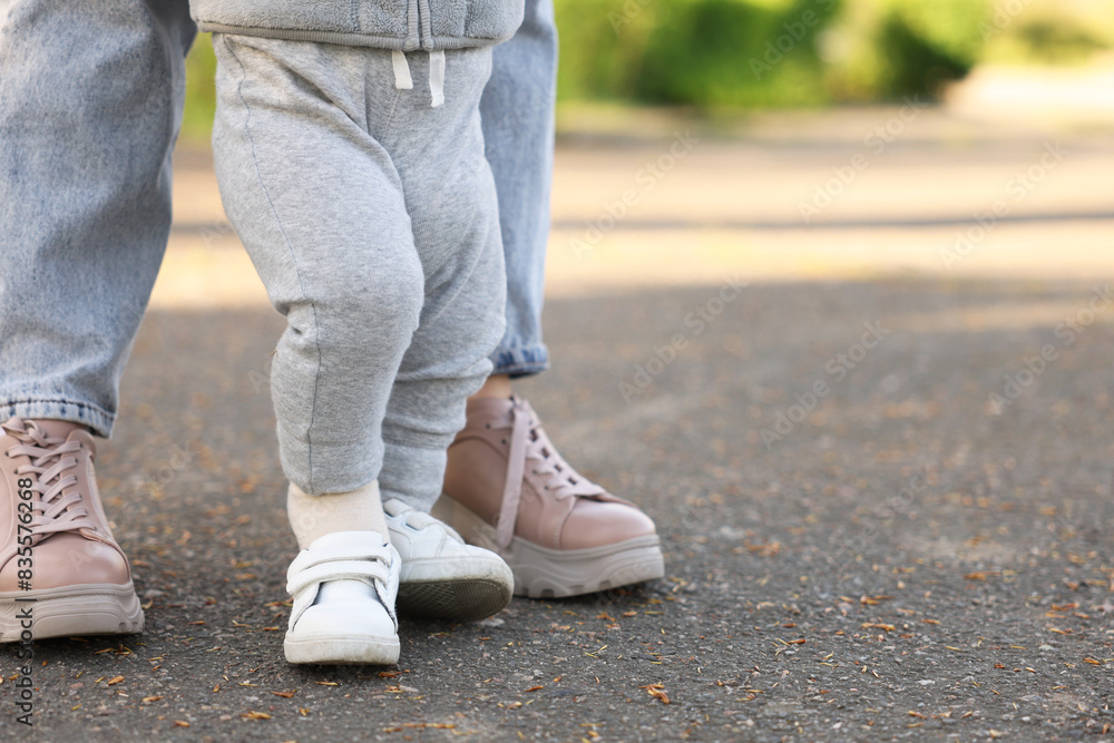 Mother teaching her baby how to walk outdoors, closeup. Space for text Mother teaching her baby how to walk outdoors, closeup. Space for text