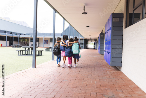 In school, four young biracial girls are walking together outdoors, copy space