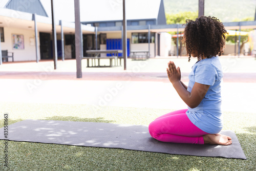 Biracial girl practices yoga at school, with copy space