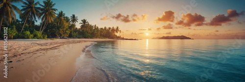 Paradise beach with palm trees and calm ocean at dawn or sunset. Panoramic banner of a peaceful landscape