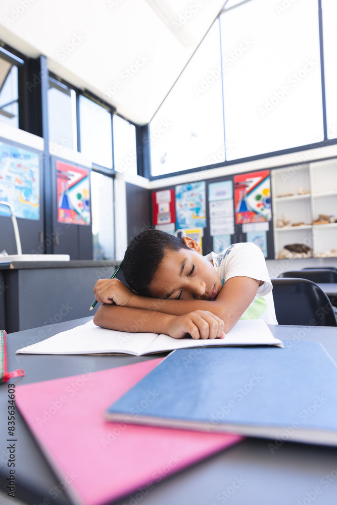 Biracial boy asleep in the classroom at school Biracial boy asleep in the classroom at school