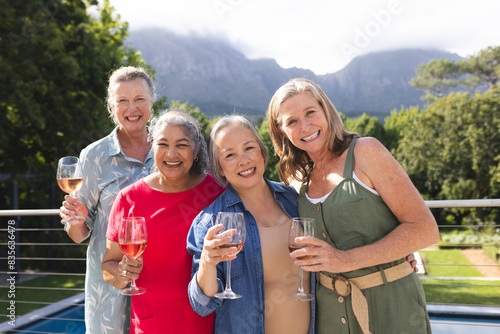 Diverse senior female friends holding drinks, enjoying outdoors