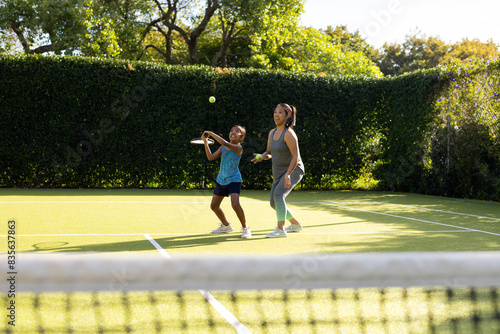 Outdoors, biracial mother and daughter playing tennis on outdoor court © WavebreakMediaMicro