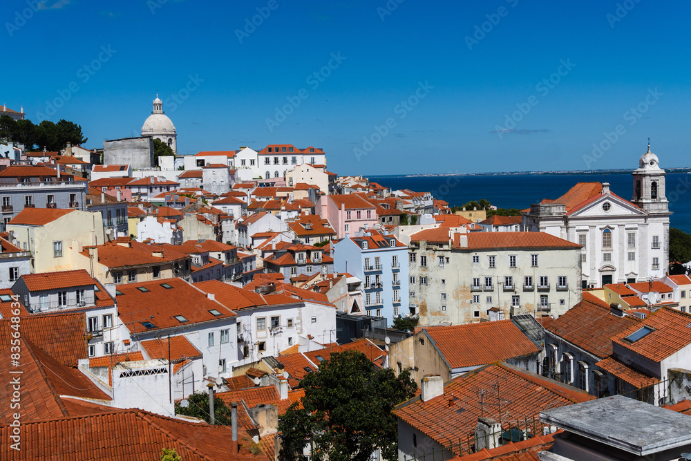 View of the beautiful skyline of Lisbon, Portugal, with red roofed, colorful houses in the Alfama district during a sunny day View of the beautiful skyline of Lisbon, Portugal, with red roofed, colorful houses in the Alfama district during a sunny day