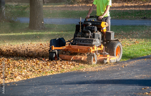 Worker on  a Standing mower and leaf mulcher, doing fall clean  up