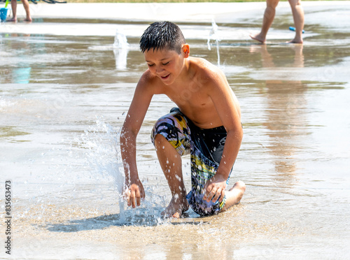 Young boy in a splash pad , plays in the water jets