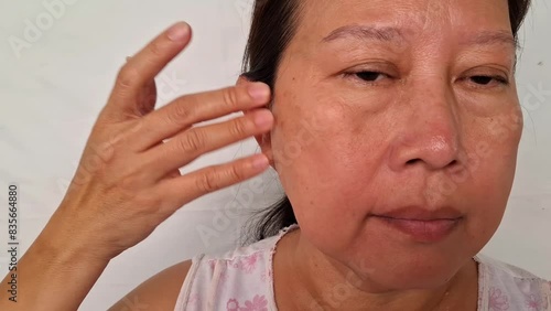 A woman uses her fingers to wipe away wrinkles on her face under the eyes.