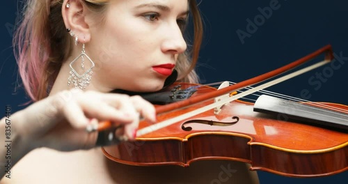 Blonde violinist with pink hair plays intently