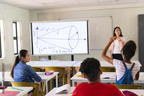 Young biracial female teacher teaches in a high school classroom, with copy space