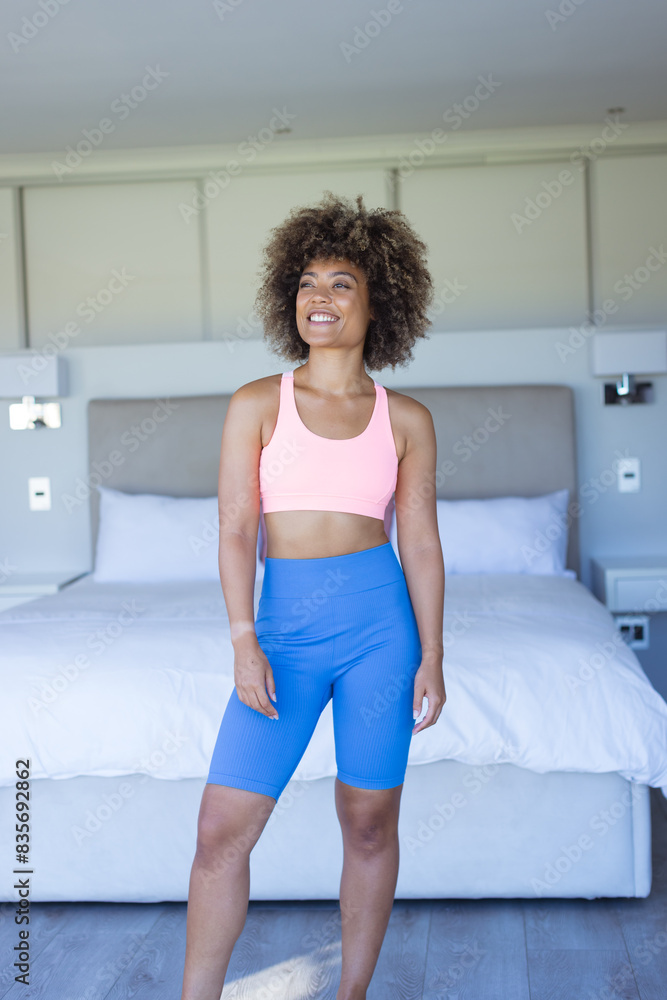 At home, biracial young female wearing blue sportswear, standing in bedroom, smiling At home, biracial young female wearing blue sportswear, standing in bedroom, smiling