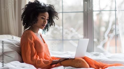 Woman at home using laptop in her bed at hom