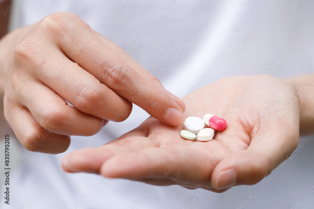 close up hand man taking multiple pills take a medicine in hand holding a cup glass of drinking water on wooden table. Stop drug use Taking Medication health care medical concept.. close up hand man taking multiple pills take a medicine in hand holding a cup glass of drinking water on wooden table. Stop drug use Taking Medication health care medical concept..