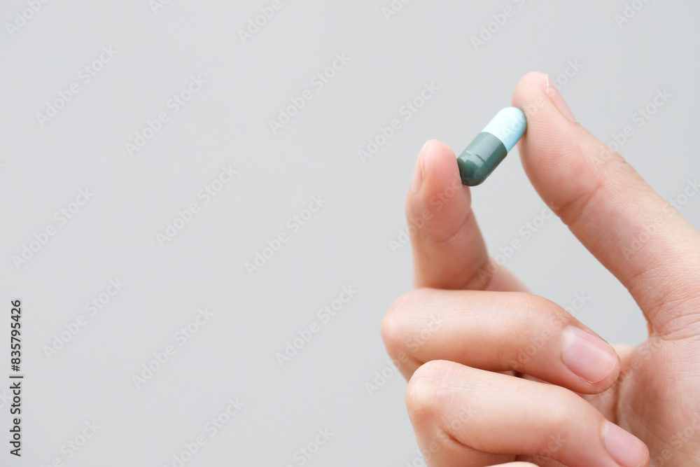 close up hand man taking multiple pills take a medicine in hand holding a cup glass of drinking water on wooden table. Stop drug use Taking Medication health care medical concept..