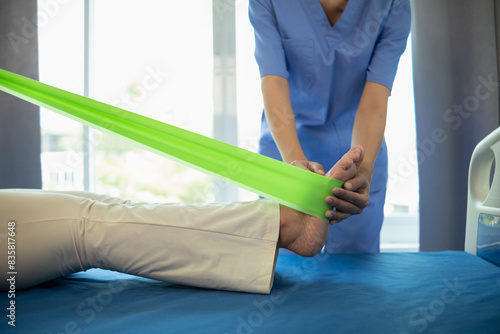 female doctor using elastic bands help patient regain muscle movement after recuperating from muscle injury and wants rehabilitate her be able use her normal daily life by practicing physical therapy photo