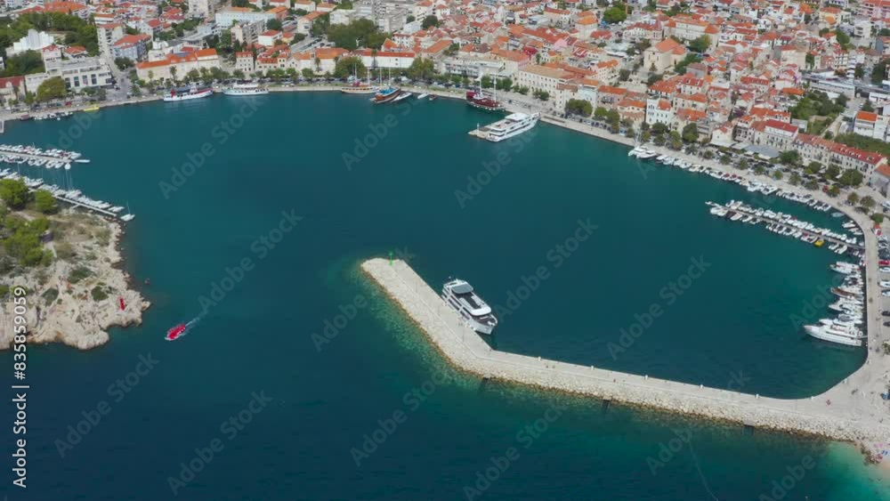 Beautiful coastline, a cozy bay with tourist, moored ships and yachts in the harbor and views of the mountains. Calm beach, traditional boats in Makarska Riviera, Croatia. Beautiful coastline, a cozy bay with tourist, moored ships and yachts in the harbor and views of the mountains. Calm beach, traditional boats in Makarska Riviera, Croatia.