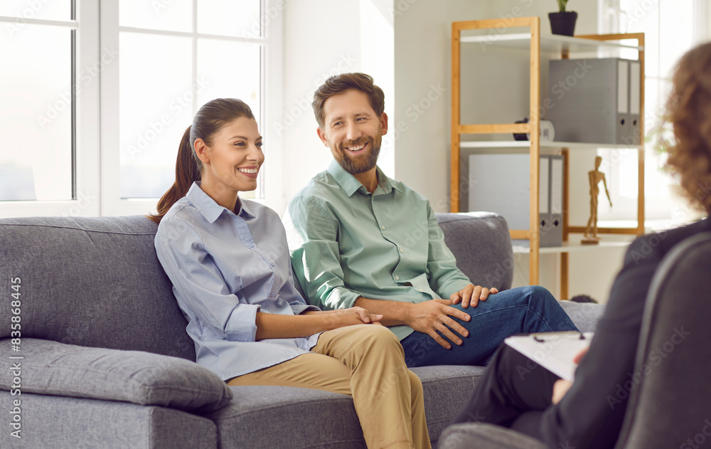 Cheerful family couple having a psychotherapy session. Happy man and woman sitting together on the sofa and discussing their marriage and relationship with their therapist. Therapy concept Cheerful family couple having a psychotherapy session. Happy man and woman sitting together on the sofa and discussing their marriage and relationship with their therapist. Therapy concept