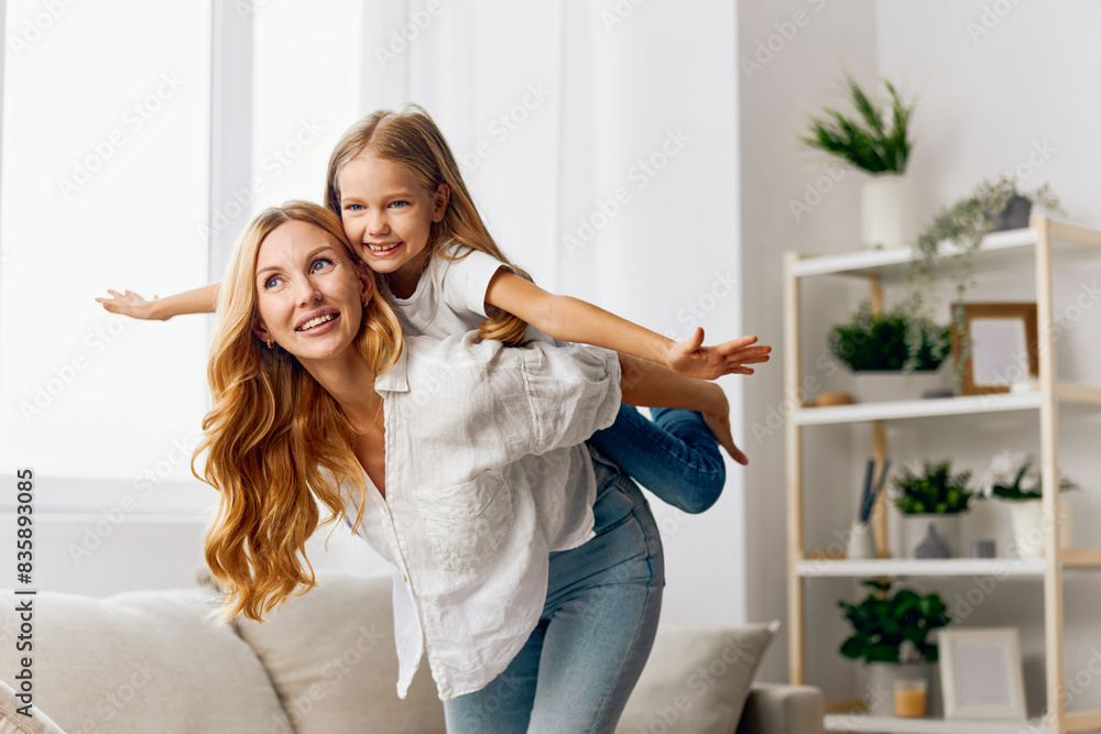 Mother and daughter laughing together on a cozy couch in a bright, modern living room filled with sunlight Mother and daughter laughing together on a cozy couch in a bright, modern living room filled with sunlight