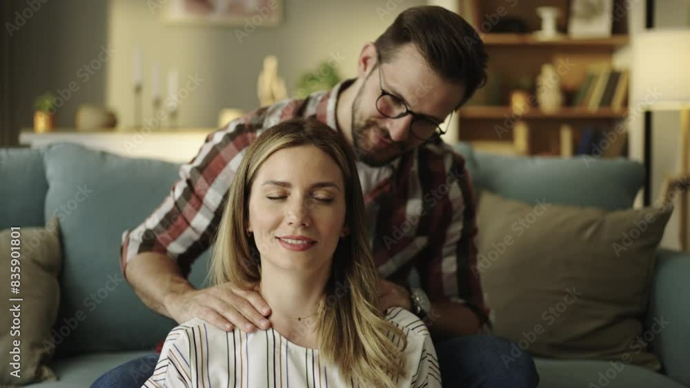 Slow-mtoion shot of a young caring husband standing behind and massaging neck of his beautiful wife. Concept of Love and care Slow-mtoion shot of a young caring husband standing behind and massaging neck of his beautiful wife. Concept of Love and care