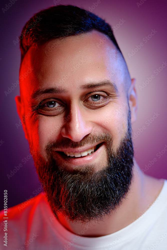 Obraz premium Studio portrait with colorful light of young handsome bearded man.