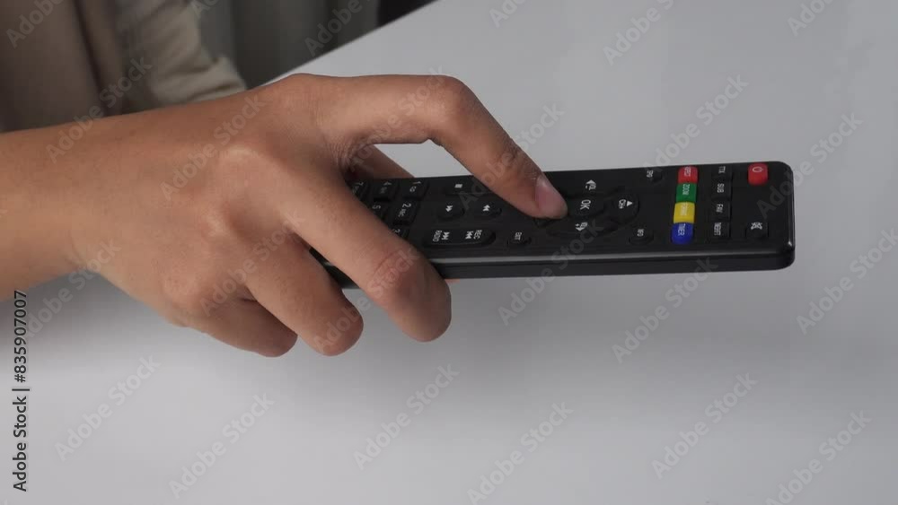 person using tv remote on white table person using tv remote on white table
