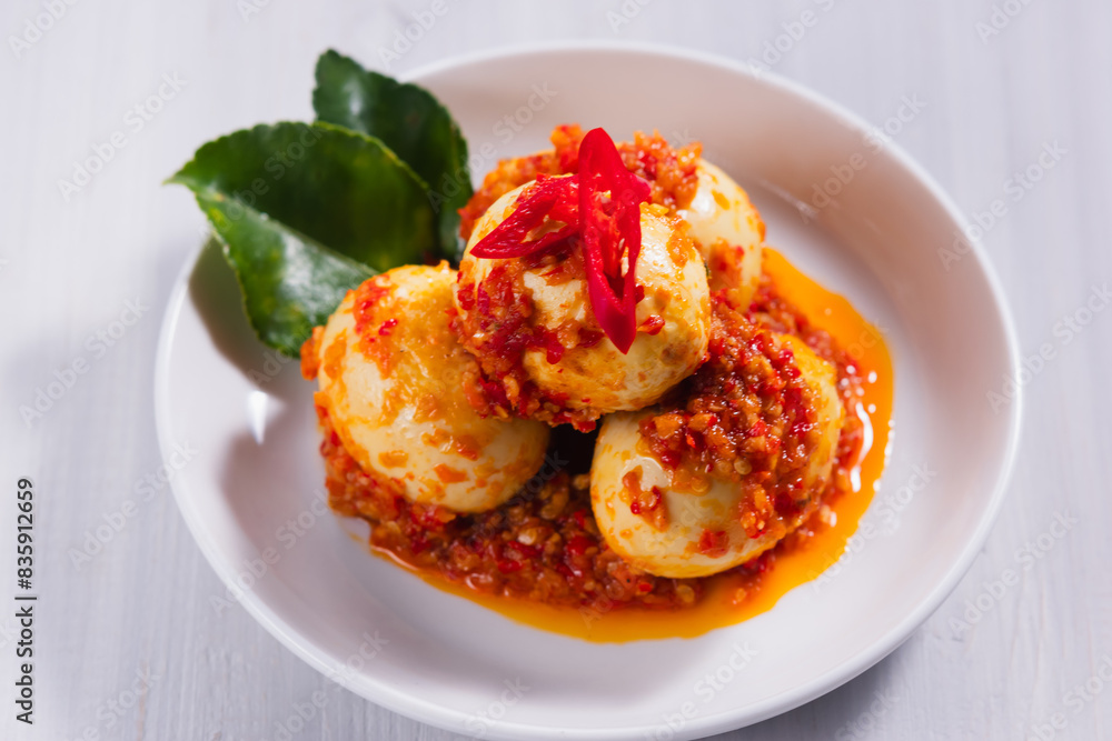 Naklejka premium Telur bumbu balado or spicy boiled egg in a white plate. with copy space. Perfect for recipe, article, or any cooking contents.