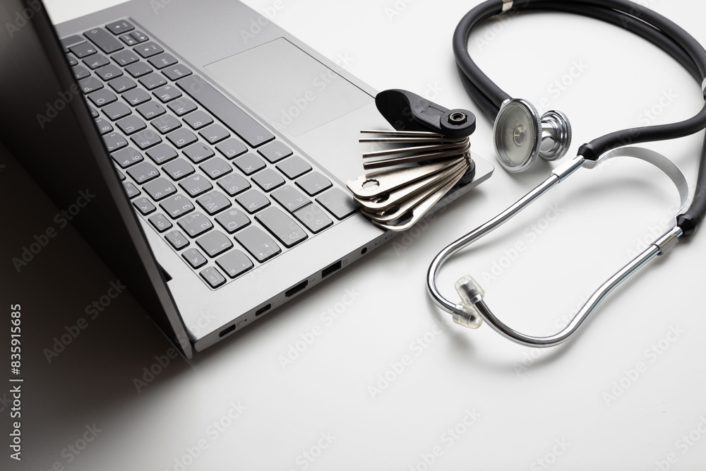 Tool and stethoscope on laptop, closeup. Concept of technical support Tool and stethoscope on laptop, closeup. Concept of technical support